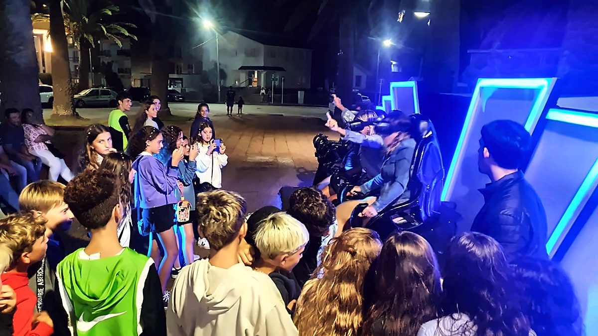 Público alrededor del cine VR Experience en la plaza, de noche